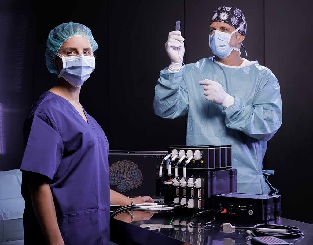 A surgeon and a nurse in an operating room, with g.HIamp and g.Estim PRO in front of them