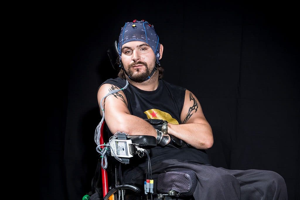 A Cybathlon competitor in a wheelchair with an EEG cap and amplifier