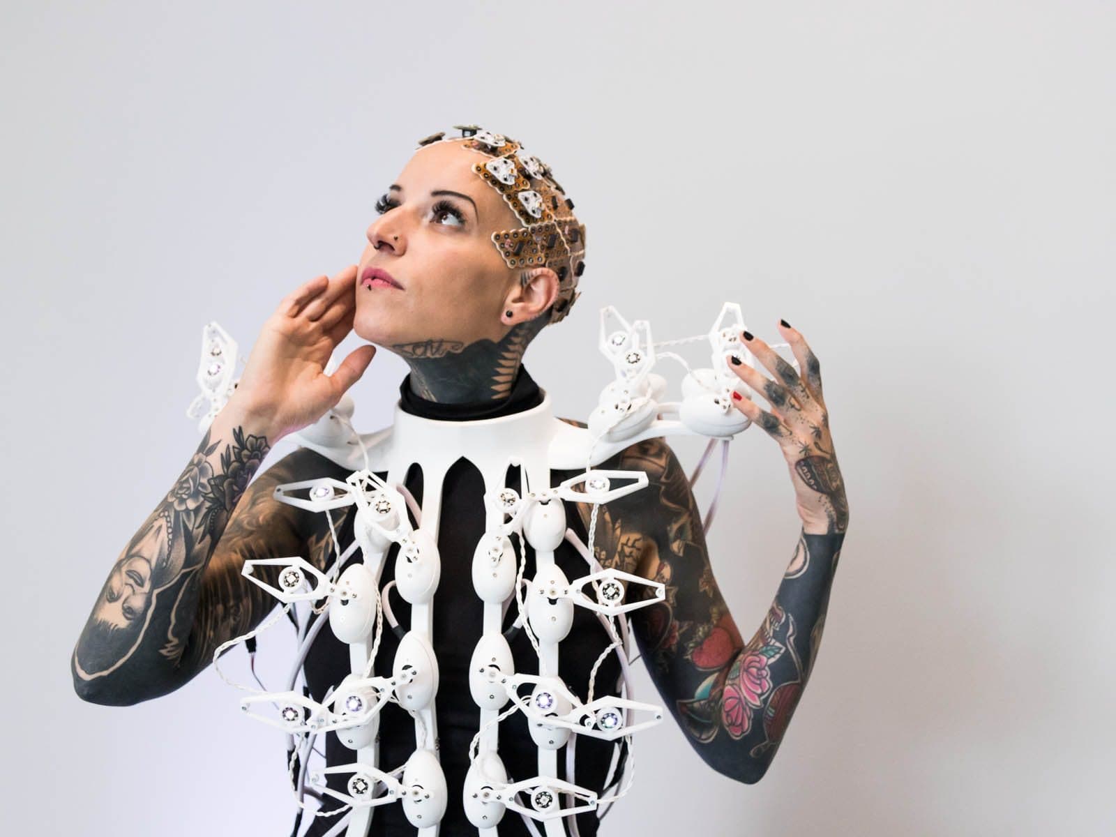 A woman wearing g.Pangolin grids on her head and a dress of white moving parts on her shoulders