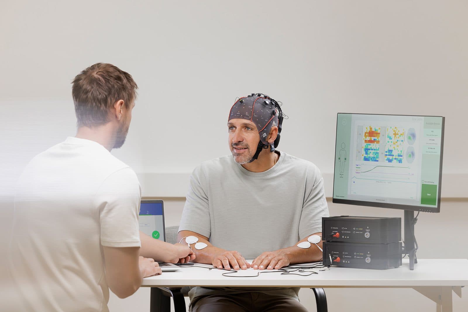 A patient in an EEG cap during a neurorehabilitation session with his therapist