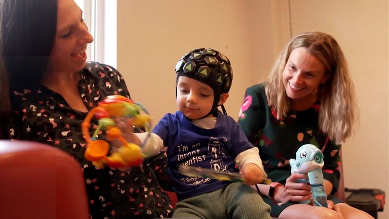 An infant in a whole-head LUMO cap playing with a toy