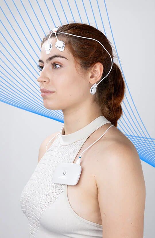 A young woman with sensors on her forehead and behind her ear, and a wireless recording unit on her chest