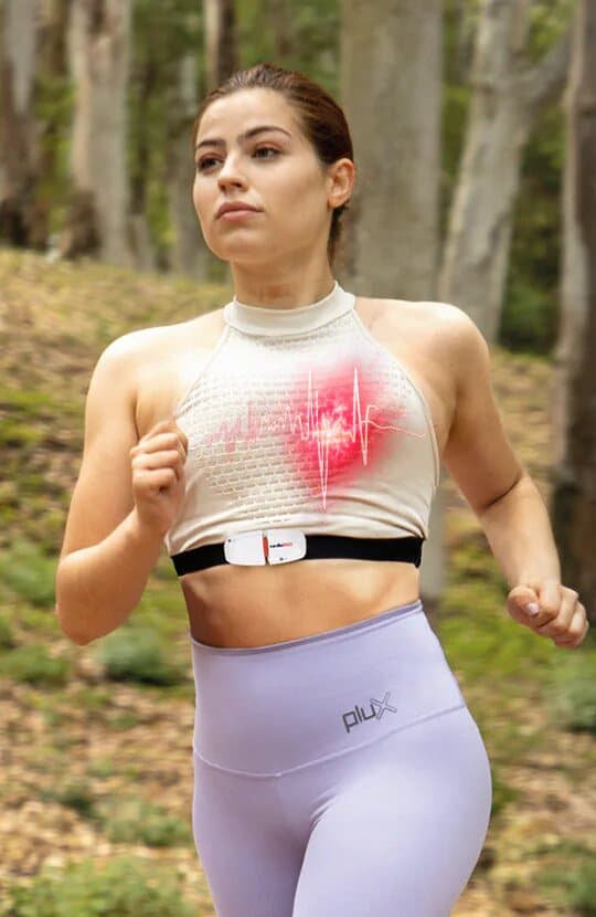 A young woman running in a forest, with a white sensor on a chest strap and a red ECG trace drawn over her heart